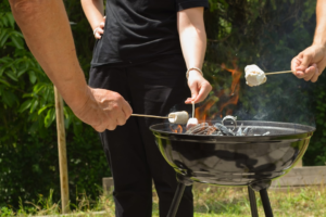 People cooking outdoors around a barbecue grill during a camping trip