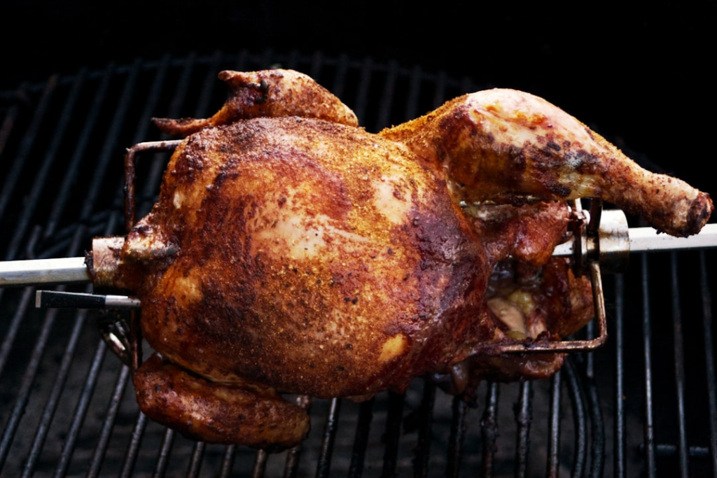 Whole chicken cooking on a grill for checking safe internal temperature