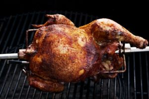 Whole chicken cooking on a grill for checking safe internal temperature